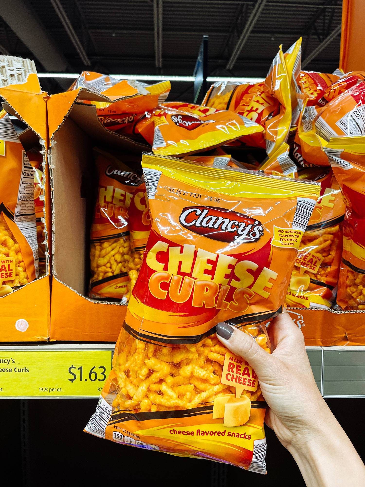 White hand holding cheese curls from ALDI.