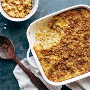 Baked mac and cheese in a pan with a wooden spoon.