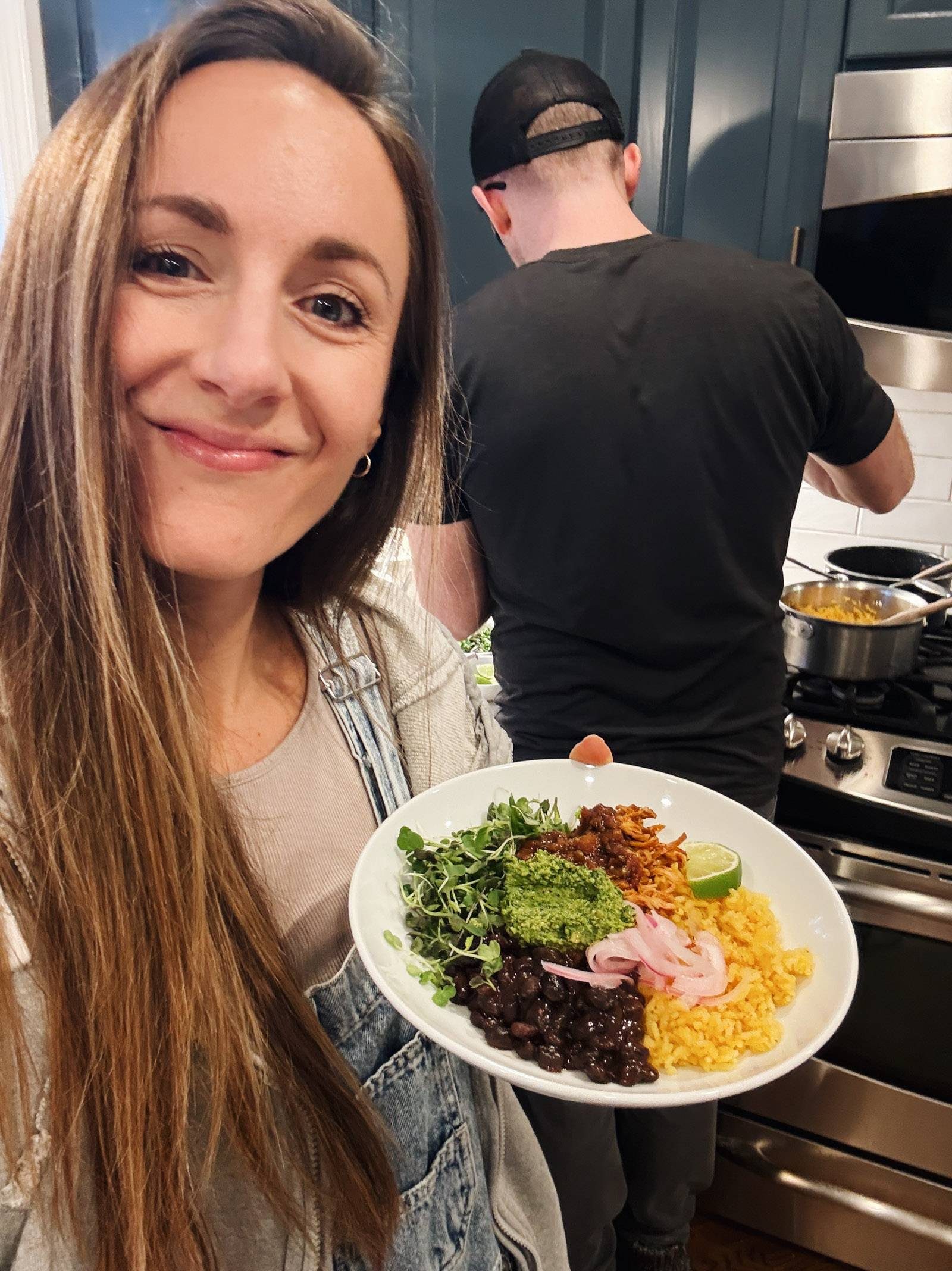 Lindsay holding a bowl of rice, beans, chicken, and cilantro pesto.