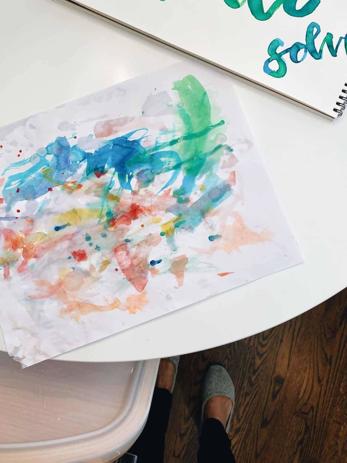 Colorful painting sitting on the edge of a round white table.