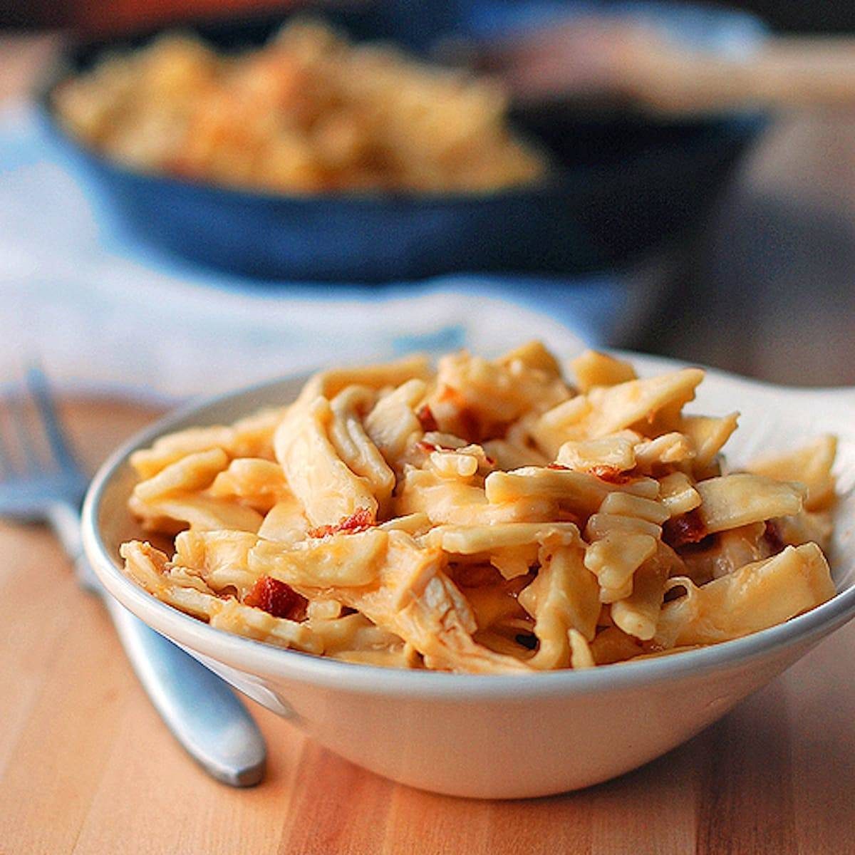 Cheesy chicken noodles coated in a creamy sauce and tossed with shredded chicken in a bowl.